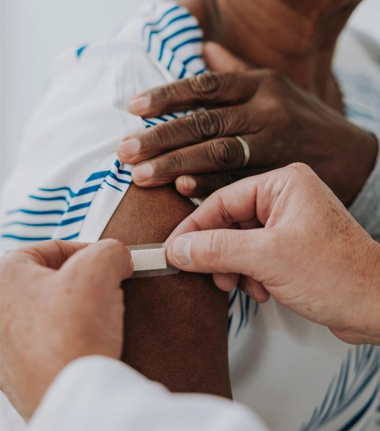 Médecin appliquant un pansement sur le bras d’une patiente