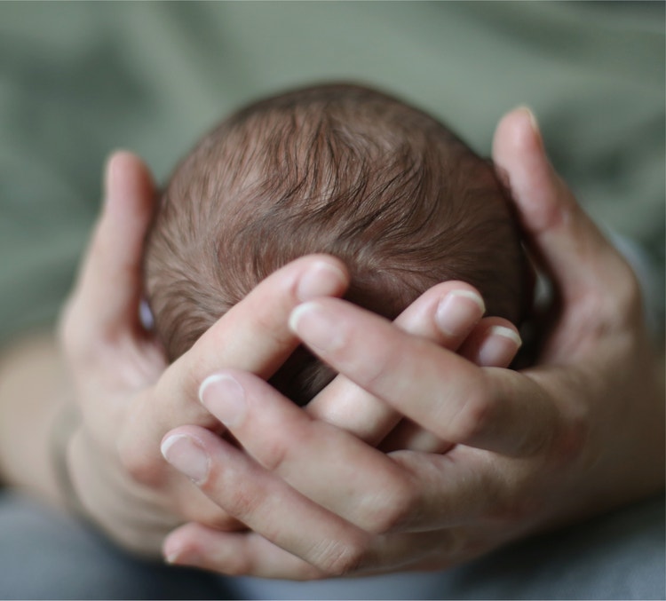 Tête du bébé entre les mains